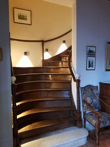 a staircase in a house with a chair and lights at LOGIS - Château de la Motte - Hôtel & Restaurant in Liessies