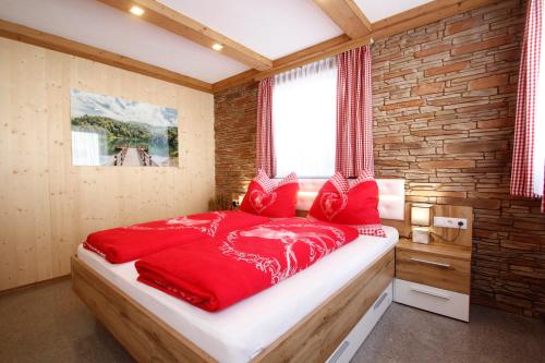 a red bed in a room with a brick wall at Appartement Almzeit mit Infrarotkabine in Großsölk