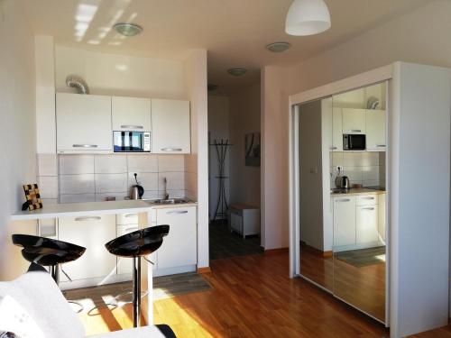 a kitchen with white cabinets and black bar stools at Apartment Olive Montenegro KO Becici in Budva