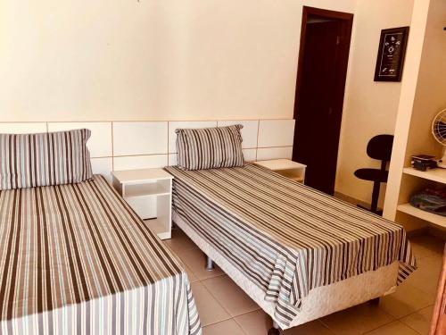 a hotel room with two beds and a chair at Margem da Lagoa Santa in Lagoa Santa