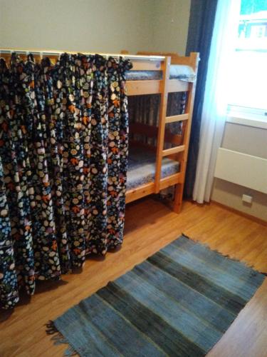 a room with a crib with a curtain and a rug at Sunne Stugcenter 18 in Gräsmark