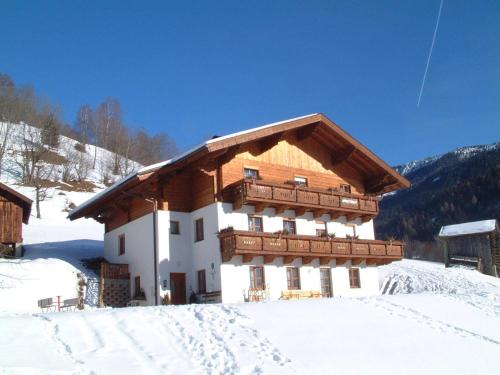 a building with a wooden roof in the snow at Appartements Hartlbauer in Dorfgastein
