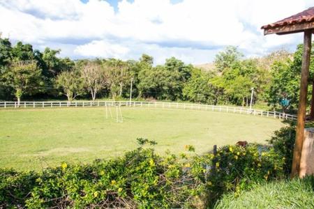 a large green field with a white fence at Hotel Fazenda Topada in Baependi