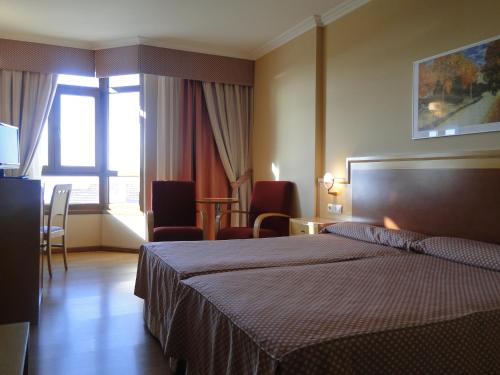 Habitación de hotel con cama, mesa y sillas en Hotel Costa Verde, en Villadesuso