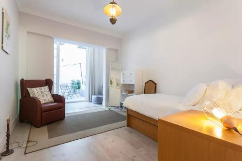 een slaapkamer met een bed, een stoel en een raam bij Graça Garden Home in Lissabon