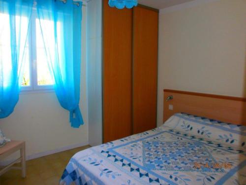 1 dormitorio con 1 cama y una ventana con cortinas azules en Les gites de lozari, en Belgodère