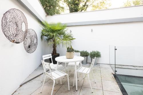 ロンドンにあるNew and Modern House for 6 Batterseaの白いテーブルと椅子(植物のあるパティオに設置)