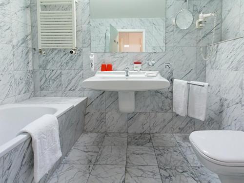 DORMERO Hotel Burghausen في بورغهاوزن: حمام أبيض مع حوض ومرحاض