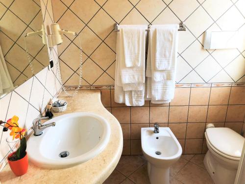 a bathroom with a sink and a toilet and towels at La Perla Hotel in SantʼAnna Arresi