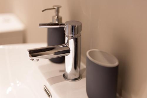 - un lavabo avec un robinet en chrome et une tasse dans l'établissement Barclay House, à Kelso