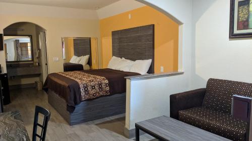 Habitación de hotel con cama y silla en Regency Inn and Suites Galena Park, en Houston