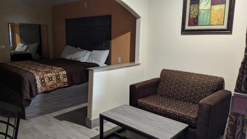 a hotel room with a bed and a chair at Regency Inn and Suites Galena Park in Houston
