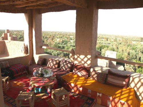 a porch with couches and a table and chairs at Auberge Migusta in Skoura