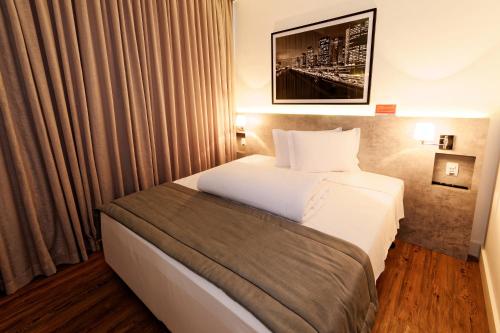 a hotel room with a bed and a window at Ramada Encore Sao Paulo Tiradentes Centro in Sao Paulo