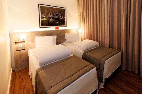 Habitación de hotel con 2 camas y cortinas en Ramada Encore Sao Paulo Tiradentes Centro, en São Paulo