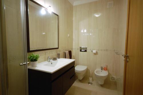 bagno con lavandino, servizi igienici e specchio di Apartamento Edificio Ibérico - Albufeira downtown ad Albufeira