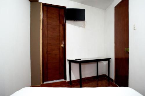 1 dormitorio con cama, mesa y puerta en Hostal Los Angeles, en Barranca