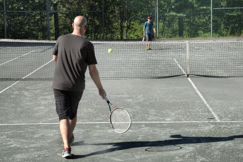 a man holding a tennis racket on a tennis court at Le Grand Lodge Mont Tremblant in Mont-Tremblant