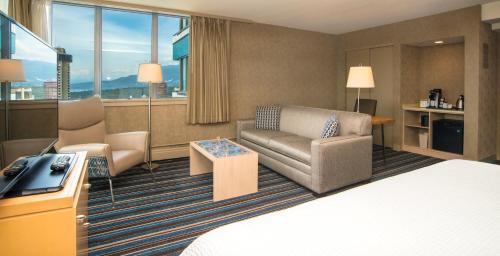 a hotel room with a bed and a couch and chair at Blue Horizon Hotel in Vancouver