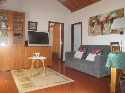 a living room with a couch and a tv at Quintinha da Chinela in Porto Judeu