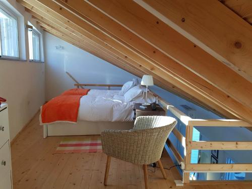 een slaapkamer met een bed en een stoel op zolder bij Casa do Meio- Farm house- Tavira in Tavira