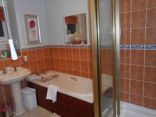 a bathroom with a bath tub and a sink at Rose Villa Bed and Breakfast in Forfar