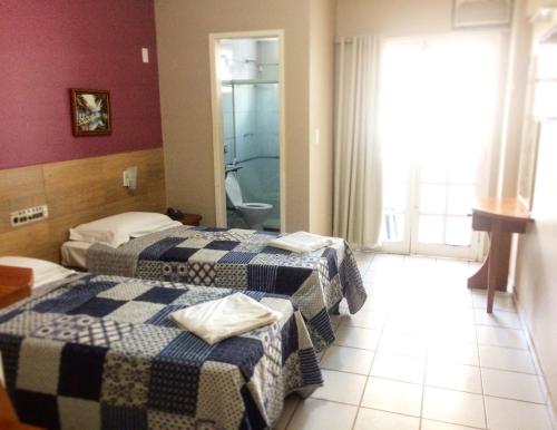 a hotel room with two beds and a bathroom at Hotel Marlin Azul in Vila Velha
