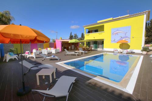 a pool with chairs and an umbrella next to a building at Villa do Lago in Silves