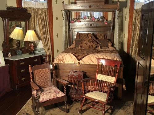 a bedroom with a bed with a mirror and two chairs at 1884 Wildwood Bed and Breakfast Inn in Hot Springs