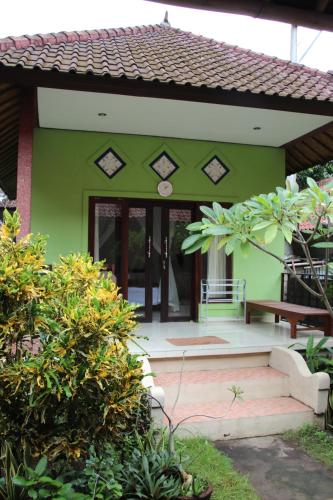 a green house with stairs leading to the front door at Taman Sandat in Amed