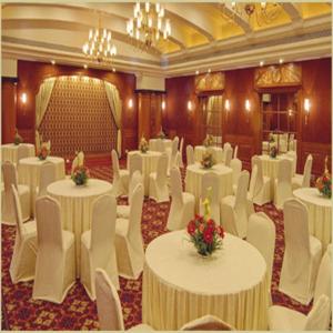 a banquet hall with white tables and white chairs at The Imperial Palace in Rajkot