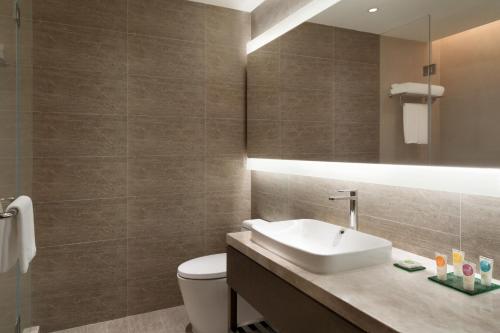 a bathroom with a sink and a toilet and a mirror at Hyatt Place Zhuhai Jinshi in Zhuhai