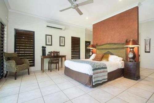 a bedroom with a large bed and a desk at Tranquility By The Course Port Douglas in Port Douglas