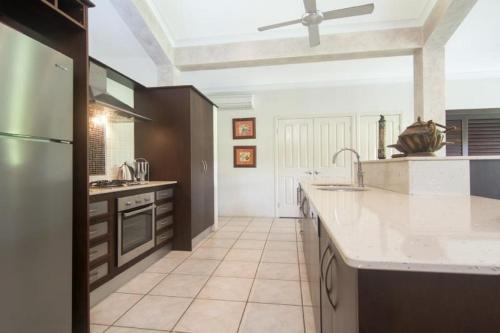 a large kitchen with white counter tops and a ceiling at Tranquility By The Course Port Douglas in Port Douglas
