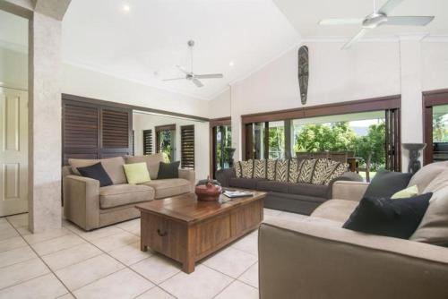 a living room with couches and a coffee table at Tranquility By The Course Port Douglas in Port Douglas