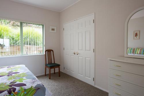 a bedroom with a bed and a dresser and a window at Ocean View B&B in Whitianga