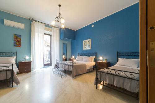 1 dormitorio con 2 camas y pared azul en Catania Inn Rooms, en Catania