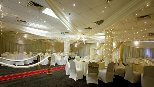 a banquet hall with white tables and white chairs at Coastlands Durban Self Catering Holiday Apartments in Durban