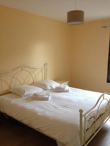 une chambre avec un lit avec des draps blancs et des oreillers dans l'établissement Angel Services - Les Mouettes, à Annecy