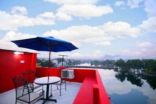 a patio with a table and chairs and an umbrella at Oolala - Your lake house in the center of Udaipur in Udaipur
