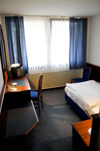 a hotel room with a bed and a desk and a bedroom at Hotel Garni Italia in Bühl