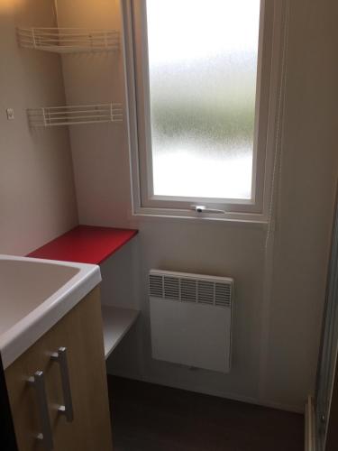 une petite salle de bains avec une fenêtre et un radiateur dans l'établissement Mobil home 6 pers, 3 ch, Kerlann**** Bretagne Sud, à Pont-Aven