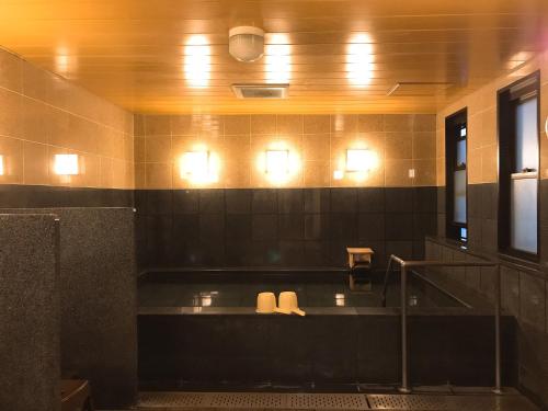 a bathroom with a bath tub with lights on the wall at Smile Hotel Namba in Osaka