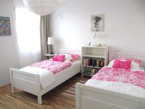 two beds in a bedroom with pink and white at Ferienwohnung Lac Konstanz in Konstanz