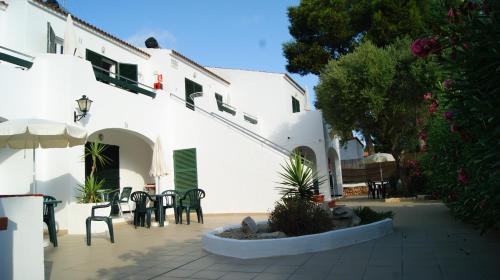 a patio with tables and chairs in front of a building at Apartaments California in Cala en Blanes