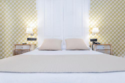 a white bed with two pillows on top of it at Hostal Oriente in Madrid