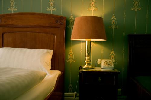 a bedroom with a bed and a lamp and a telephone at Hotel-Pension Funk am Kurfürstendamm in Berlin