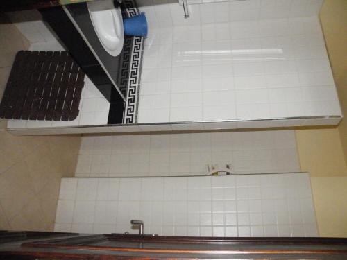 a kitchen with a sink and a white tiled wall at Draga, Agadir appart et piscine dans villa, in Cite Adrar
