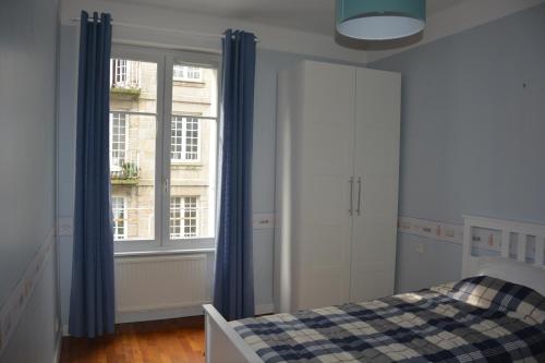 una camera con letto e finestra con tende blu di Jacques MELCHIOR meublé de tourisme 3 étoiles Intra Muros a Saint Malo