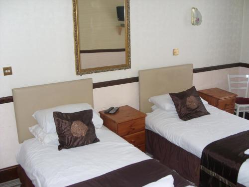 Habitación de hotel con 2 camas y espejo en Phoenix Hotel en Chard